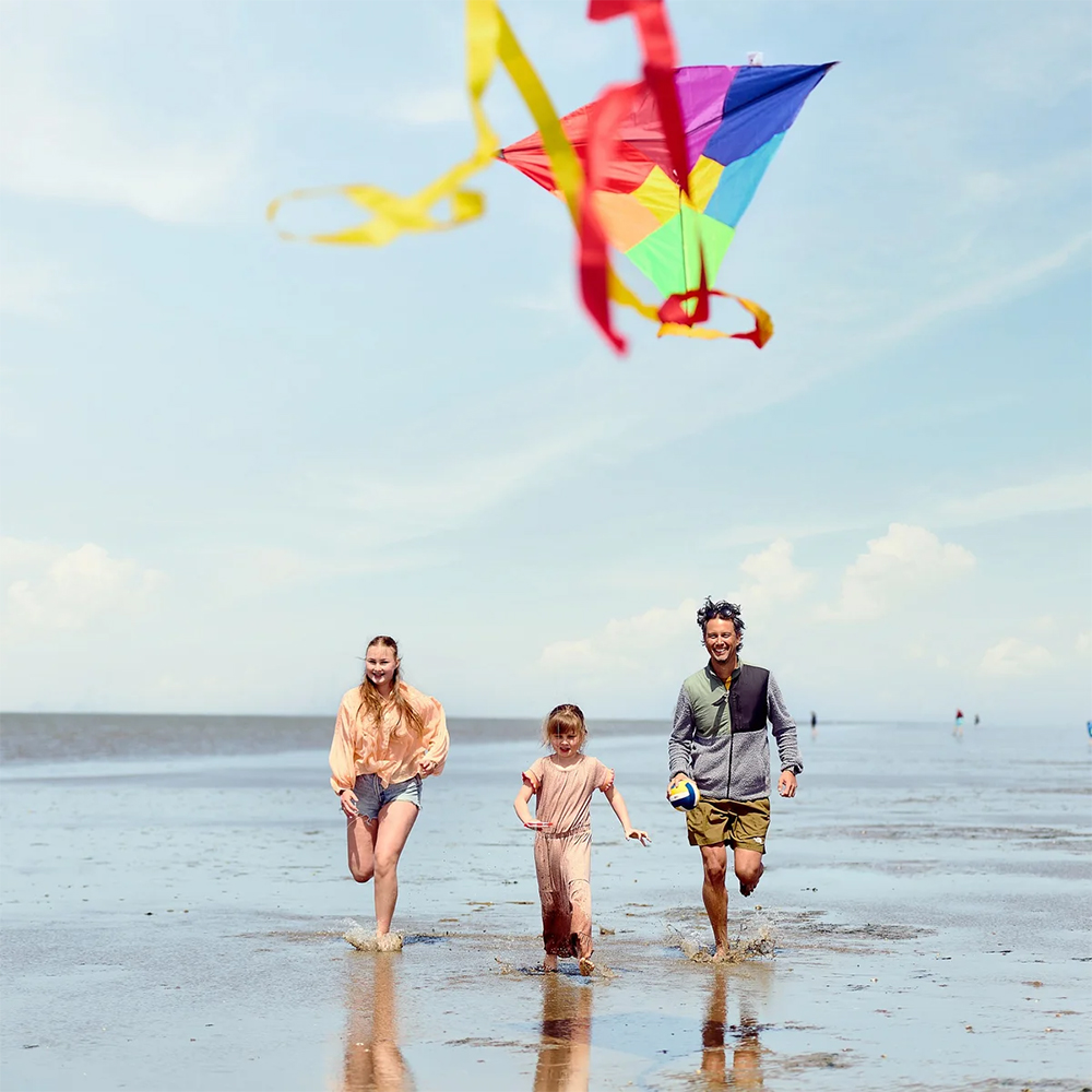 Familie am Strand mit buntem Drachen in der Luft