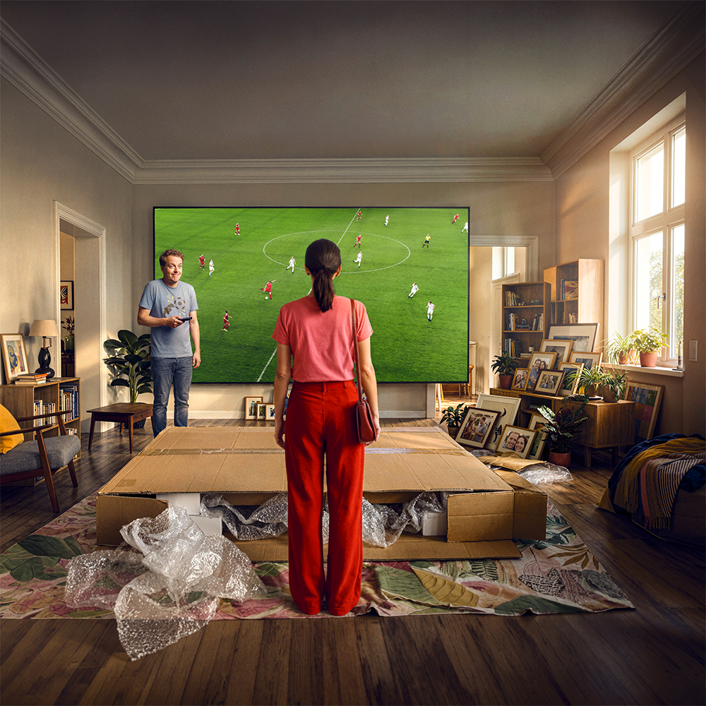 Zwei Personen richten einen großen Fernseher im Wohnzimmer ein